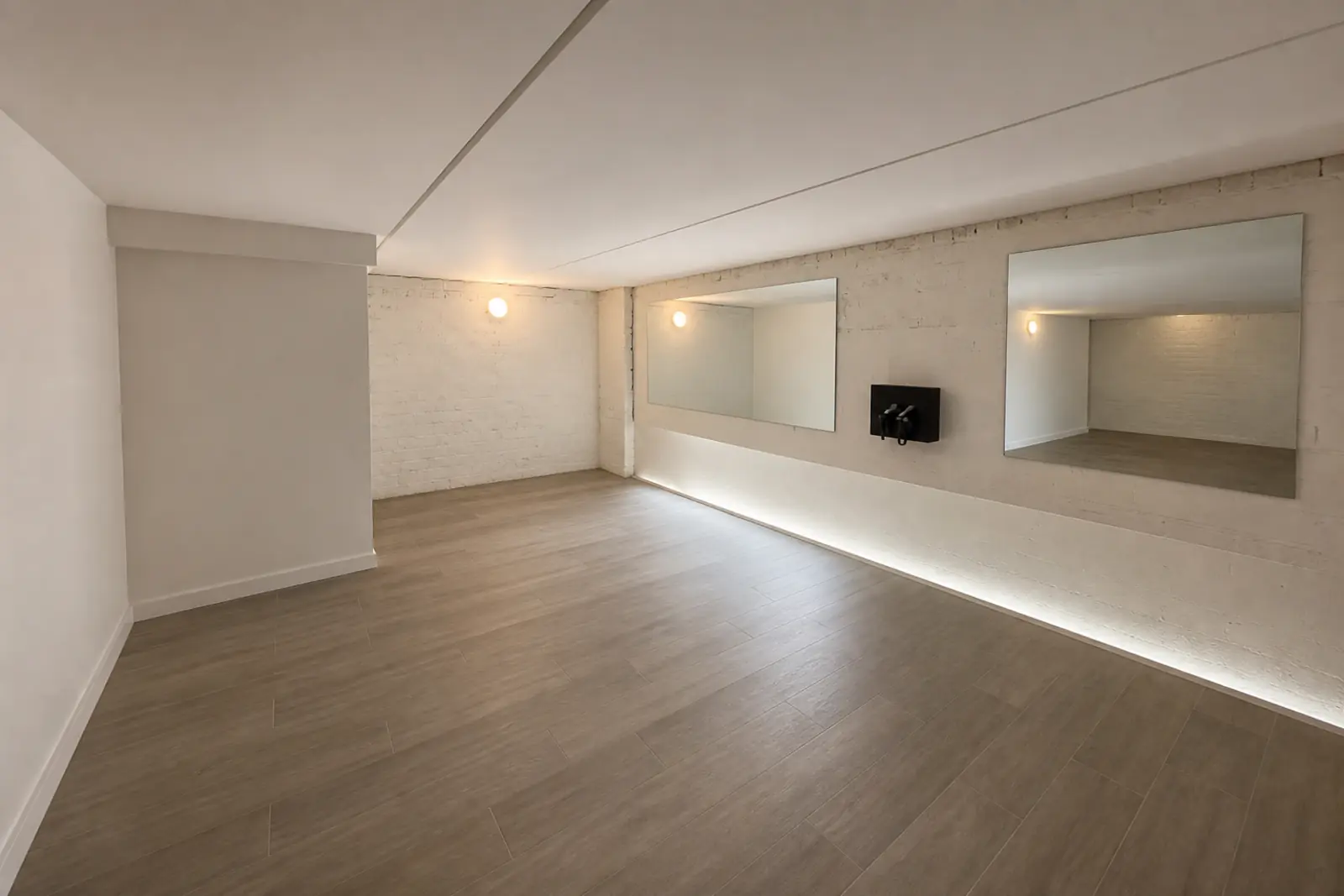 The mobility area: white plaster walls, two wide wall mirrors above a rail, and the massage-gun station beside them